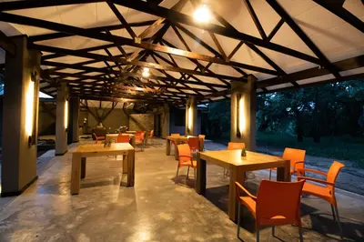 a restaurant with wooden tables and orange chairs at Little Africa Safari Lodge in Hoedspruit