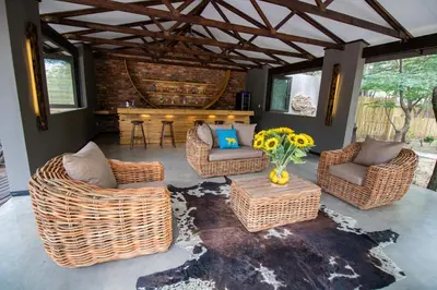 a living room with wicker furniture and a fireplace at Little Africa Safari Lodge in Hoedspruit