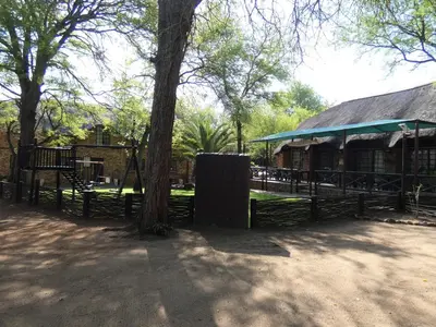 a fence with a tree in front of a building at Weltevrede Lodge - Self Catering Houses in Marloth Park
