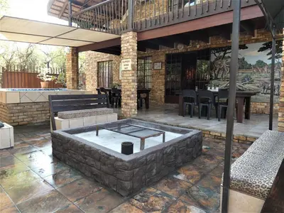 an outdoor patio with a stone fire pit at Weltevrede Lodge - Self Catering Houses in Marloth Park