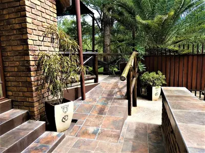 a patio with potted plants and a wooden fence at Weltevrede Lodge - Self Catering Houses in Marloth Park