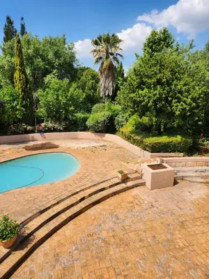 a swimming pool in a garden with a palm tree at Fhamoni House in Centurion