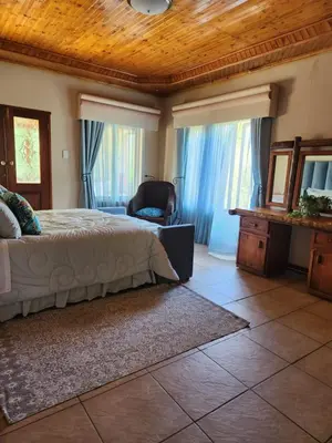 a bedroom with a bed and a chair and windows at Fhamoni House in Centurion