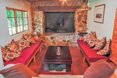 a living room with red couches and a stone fireplace at Skye High House & Cottage in Dullstroom