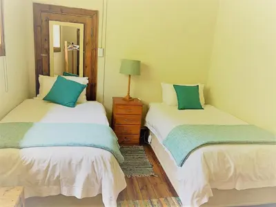 a bedroom with two beds and a dresser and a mirror at Skye High House & Cottage in Dullstroom