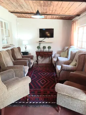 a living room with couches and a flat screen tv at Skye High House & Cottage in Dullstroom