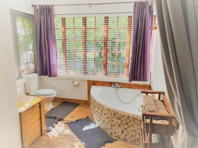 a bathroom with a large tub and a window at Skye High House & Cottage in Dullstroom