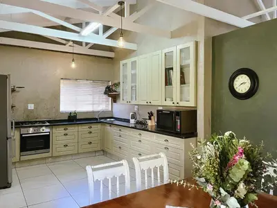 a kitchen with white cabinets and a table and a clock at Rondebossie Farm Retreat in Magoebaskloof