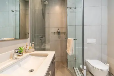 a bathroom with a shower and a sink and a toilet at Top Floor Menlyn Maine studio apartment with Stunning Views & No Load Shedding in Pretoria
