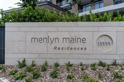 a sign in front of a building with a building at Top Floor Menlyn Maine studio apartment with Stunning Views & No Load Shedding in Pretoria