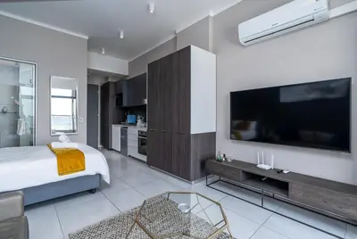 a bedroom with a bed and a large television at Top Floor Menlyn Maine studio apartment with Stunning Views & No Load Shedding in Pretoria