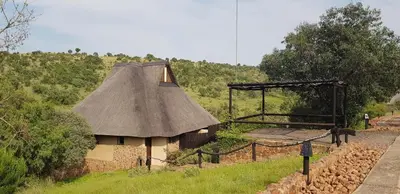 a small house with a thatch roof on a hill at Schrikkloof Private Nature Reserve, home of The Lions Foundation in Bela-Bela