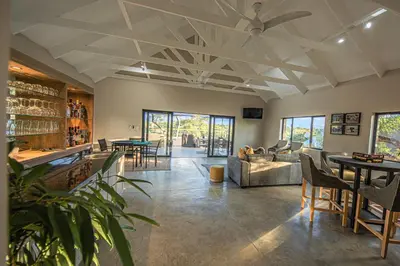 a living room with a ceiling fan and tables at Little Kubu Lodge in Hoedspruit