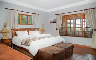 a bedroom with a large bed and windows at Moonlight Meadows just outside Dullstoom in Dullstroom