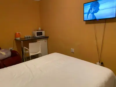 a hotel room with a bed and a tv on the wall at Mankweng lodge in Polokwane