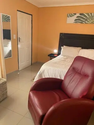 a bedroom with a bed and a red leather chair at Mankweng lodge in Polokwane