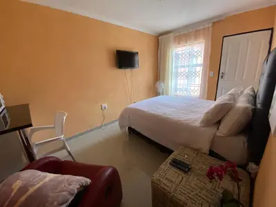 a bedroom with a bed and a couch and a chair at Mankweng lodge in Polokwane