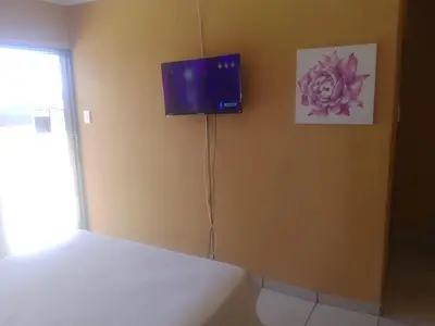 a bedroom with a bed and a tv on the wall at Mankweng lodge in Polokwane