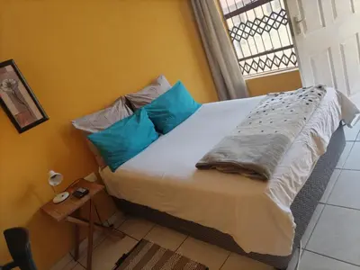 a bedroom with a bed with blue pillows and a window at Mankweng lodge in Polokwane