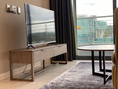 a television on a wooden stand in a room with a table at Menlyn Maine Trilogy 11th Floor in Pretoria