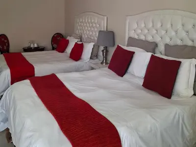 a bedroom with two beds with red and white pillows at Serene Pastures in Midrand
