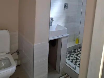 a bathroom with a sink and a shower and a toilet at Serene Pastures in Midrand