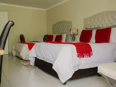 a bedroom with two beds with red and white pillows at Serene Pastures in Midrand