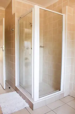 a shower with a glass door in a bathroom at Dumelang Executive Lodge- OFF-GRID Solar powered Midrand in Midrand