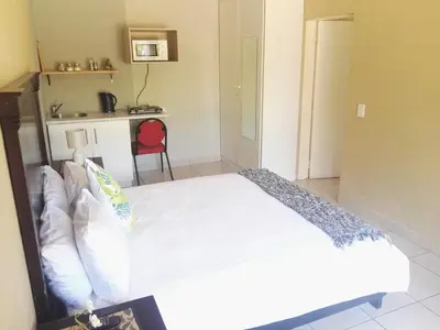 a bedroom with a white bed and a red chair at Dumelang Executive Lodge- OFF-GRID Solar powered Midrand in Midrand