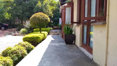 a sidewalk next to a building with bushes and a window at Dumelang Executive Lodge- OFF-GRID Solar powered Midrand in Midrand