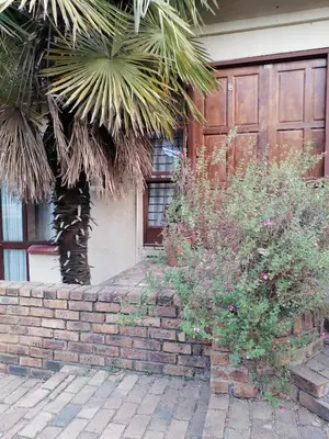 a house with a palm tree in front of a brick wall at Dumelang Executive Lodge- OFF-GRID Solar powered Midrand in Midrand