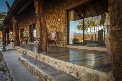 a porch of a stone building with a chair and windows at No 43 - The Eco Lodge in Hoedspruit