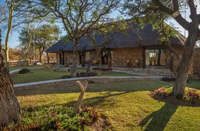 a building with a thatched roof in a park at No 43 - The Eco Lodge in Hoedspruit