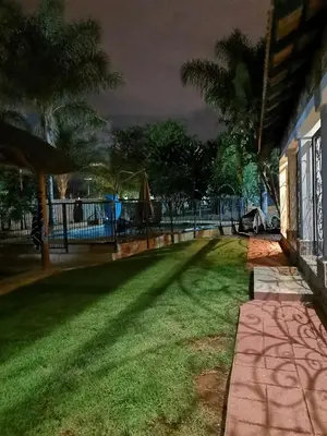 a yard with a playground in the background at night at Klyne Jiweel Guesthouse in Pretoria