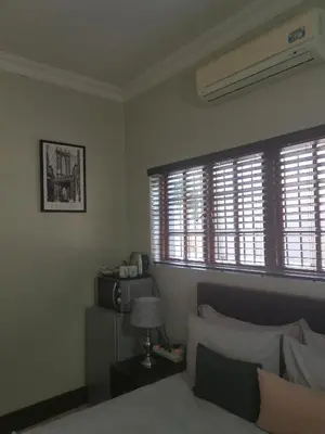 a bedroom with a bed and two windows at Klyne Jiweel Guesthouse in Pretoria