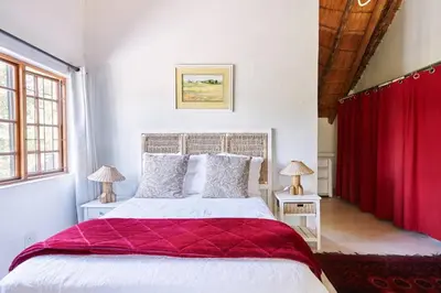 a bedroom with a large bed with red curtains at 41 Ridge- self catering cottages in Midrand