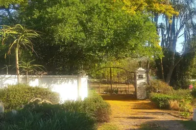 a garden with a fence and a gate and trees at 41 Ridge- self catering cottages in Midrand