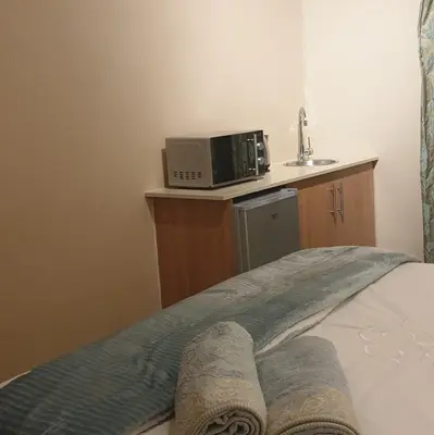 a bedroom with a bed with a microwave and a sink at Langa's Gabedi Goshen in Pretoria
