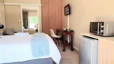 a hotel room with a bed and a tv and a desk at Langa's Gabedi Goshen in Pretoria