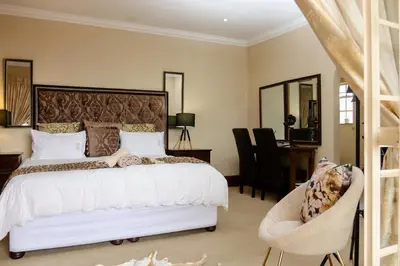 a bedroom with a bed and a chair and a desk at TDM's Boutique Guest House in Pretoria