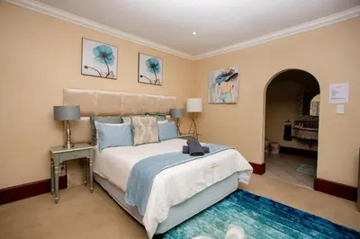 a bedroom with a large bed with blue pillows at TDM's Boutique Guest House in Pretoria