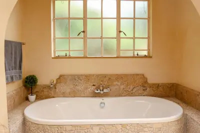 a bath tub in a bathroom with a window at TDM's Boutique Guest House in Pretoria