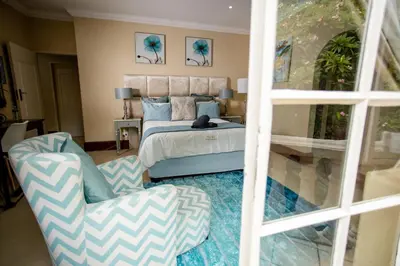 a bedroom with a bed and a couch and a chair at TDM's Boutique Guest House in Pretoria
