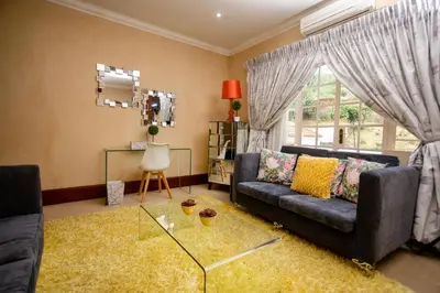 a living room with a couch and a glass table at TDM's Boutique Guest House in Pretoria