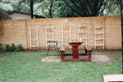 a wooden bench and a table in front of a brick wall at Bosveldrus Gastehuis in Vaalwater