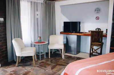 a hotel room with a bed and a table and chairs at Bosveldrus Gastehuis in Vaalwater