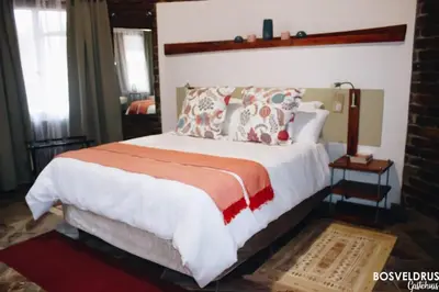 a bedroom with a large white bed with pillows at Bosveldrus Gastehuis in Vaalwater