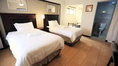 a hotel room with two beds and a toilet at Floreat Riverside Lodge and Spa in Sabie