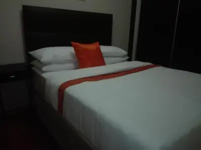 a white bed with a red pillow on top of it at MixoSunrise Guesthouse & Spa in Pretoria