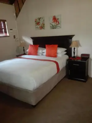 a bedroom with a large white bed with red pillows at MixoSunrise Guesthouse & Spa in Pretoria
